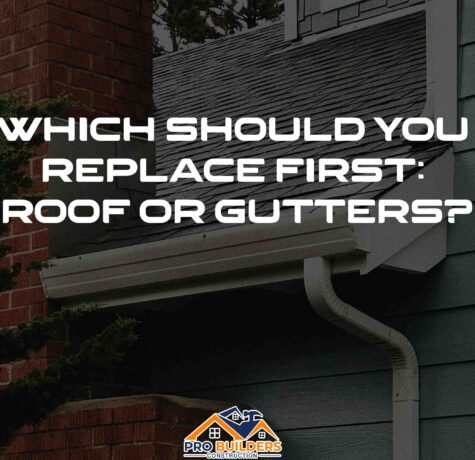 A house with a brick chimney and a gray roof. The gutters are white and there is a downspout visible. The text on the image reads: "WHICH SHOULD YOU REPLACE FIRST: ROOF OR GUTTERS?"