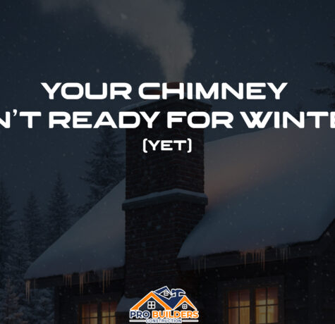 A photograph of a cozy brick home in winter, its roof and chimney covered in snow. Light smoke drifts from the chimney, and warm light glows from the windows during a gentle twilight snowfall.