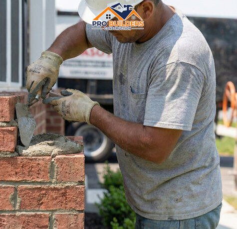 Construction worker laying natural stone blocks with mortar and trowel.